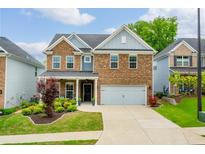 Two-story brick home with an attached two-car garage, manicured lawn, and a charming covered porch at 123 Woodford Ln, Canton, GA 30115