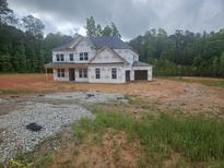Unfinished two-story home with visible framework and a lush green backdrop showcases potential at 3301 Lions Ruby Ln, Atlanta, GA 30349