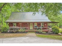 Charming cottage-style home with a metal roof, inviting front porch and attractive landscaping at 5419 Tyree Rd, Winston, GA 30187