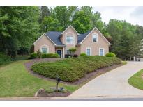 Charming tan home featuring lush landscaping, a curved driveway, and a welcoming front entrance at 1720 Ivey Trce, Cumming, GA 30041