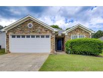 Charming single-story home featuring a stone facade, two-car garage, and well-manicured lawn at 10892 Big Sky Dr, Hampton, GA 30228
