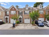 Charming brick townhouse with an attached garage, mature landscaping and front yard parking spaces at 1880 Garbrooke Cv, Lawrenceville, GA 30046
