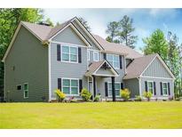 Charming two-story home featuring green siding, black shutters, lush lawn, and manicured landscaping at 445 Boulder Crest Trl, Villa Rica, GA 30180