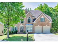 Charming brick home with two-car garage, manicured lawn, and lush landscaping offers great curb appeal at 902 Preserve Bluff Dr, Buford, GA 30518