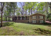 Charming brick home with a spacious carport, surrounded by lush trees and a well-maintained lawn at 4730 Geneva Sw Dr, Lilburn, GA 30047