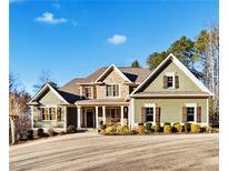 Charming two-story home showcasing stone accents, green siding, and manicured landscaping at 121 Harmony Oaks Trl, Canton, GA 30115