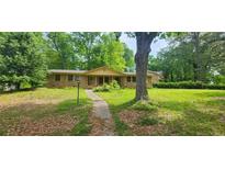 Charming single-story home featuring a brick exterior and a spacious front yard with mature trees and a stone pathway at 2886 The Fontainebleau Sw, Atlanta, GA 30331