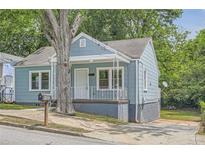 Charming blue bungalow with white trim, front porch, and well-maintained landscaping at 1002 Ira Sw St, Atlanta, GA 30310
