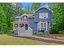 Charming blue two-story home featuring a welcoming front porch and lush, landscaped front yard at 4440 Coventry Ne Ct, Roswell, GA 30075