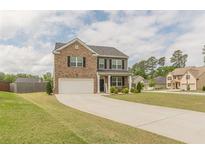 Inviting two-story home featuring a brick facade, well-manicured lawn, and a spacious driveway leading to a two-car garage at 3868 Sweet Iris Cir, Loganville, GA 30052