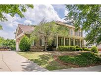 Charming two-story brick home boasts a manicured lawn and a welcoming covered front porch at 4891 Tarry Post Ln, Suwanee, GA 30024