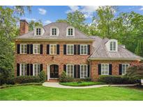 Charming brick home with black shutters, a manicured lawn and lush landscaping at 4555 Peachtree Dunwoody Rd, Sandy Springs, GA 30342