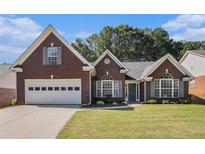 Charming brick home featuring a two-car garage, well-manicured lawn, and classic architectural details at 1180 Chandler Ridge Dr, Lawrenceville, GA 30045