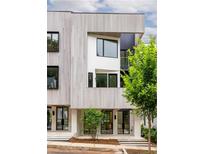 Modern three-story townhouse with clean lines and a light-colored facade, accented by dark window frames and lush greenery at 11548 Serenbe Ln, Chattahoochee Hills, GA 30268