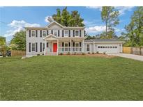 Charming two-story home with a bright red front door and covered porch at 565 Deer Sw Run, Lilburn, GA 30047