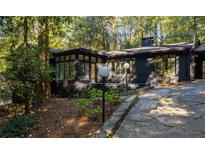 Stunning exterior of a black painted brick home with a private driveway and lush landscaping at 922 Barton Woods Ne Rd, Atlanta, GA 30307
