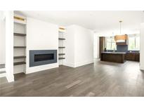 Open-concept living room with fireplace, built-in shelves and view of kitchen at 11554 Serenbe Ln, Chattahoochee Hills, GA 30268