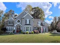 Elegant two-story home with stone and stucco exterior, manicured lawn, and mature trees at 2645 Preston Ridge Ln, Dacula, GA 30019