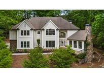 Stunning home featuring manicured landscaping, a stone chimney, and an inviting entrance with a large window feature at 310 Tradea Tarn, Roswell, GA 30076