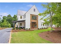 Stunning two-story modern farmhouse with metal roof and manicured lawn on a sunny day at 12520 Celestine Way, Milton, GA 30075