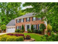 Beautiful two-story brick home with lush landscaping and mature trees providing ample shade at 615 Woodwork Way, Roswell, GA 30076