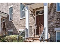 Charming brick townhome entrance featuring a wooden door, white pillars, and a clear house number at 2119 Dee Dee Muse Nw Ln, Atlanta, GA 30318