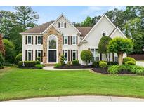 Charming two-story home featuring stone accents, a well-manicured lawn, and lush landscaping at 1008 Stream Valley Ct, Alpharetta, GA 30022