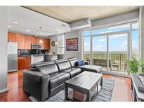 Modern condo living room with black leather sectional, wood floors, and a balcony overlooking a cityscape at 250 Pharr Ne Rd # 1914, Atlanta, GA 30305