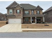 Two-story home with brick and siding, attached two-car garage, covered front porch and manicured lawn at 3566 Andover Way, Buford, GA 30519