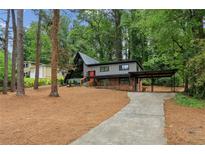 Striking two-story house featuring a carport and angular architectural details nestled in a lush, wooded landscape at 3567 Beachhill Dr, Atlanta, GA 30340