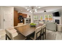 Open concept living room and kitchen featuring modern lighting, a fireplace, and a large dining table at 690 Cobblestone Creek Ln, Mableton, GA 30126