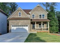 Charming two-story brick home featuring a covered front porch and attached two-car garage at 194 Jennifer Nw Ln, Lilburn, GA 30047