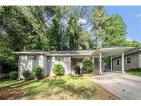 Charming single-story home with carport, red door, lush lawn, and mature trees at 2044 Glendale Dr, Decatur, GA 30032