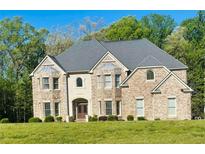 Stunning brick two-story home with a manicured lawn and lush surrounding greenery at 209 Kingscastle Dr, Ellenwood, GA 30294