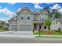 Beautiful two-story home with gray brick, three-car garage, and craftsman style front porch at 11305 Knollwood Bend, Johns Creek, GA 30097