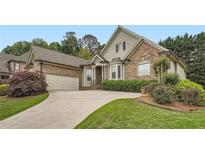 Beautiful stone and shingle home with a manicured lawn and a curved driveway leading to an attached garage at 1025 Ector Nw Dr, Kennesaw, GA 30152
