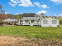 Charming single-story home with a covered porch, white siding, and a spacious front yard at 1871 Weems Rd, Locust Grove, GA 30248