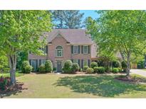Charming two-story brick home with a well-manicured lawn and mature trees, offering great curb appeal at 630 Silverberry Ln, Sugar Hill, GA 30518