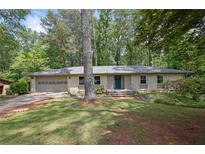 Charming brick home with a two-car garage, lush greenery, and a welcoming front entrance at 4420 Lake Breeze Dr, Stone Mountain, GA 30083