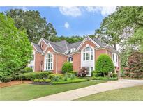Stately brick home featuring manicured landscaping, large windows, and a well-maintained lawn at 452 Brushstroke Se Ct, Marietta, GA 30067