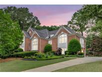 Stately brick home featuring manicured landscaping, mature trees, and elegant architectural details at 452 Brushstroke Se Ct, Marietta, GA 30067