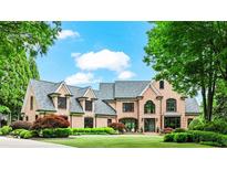 Impressive brick home featuring manicured landscaping, a large lawn, and architectural roof lines at 6515 Ashbourne Ct, Suwanee, GA 30024