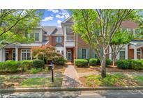 Charming two-story brick townhome with well-manicured landscaping, trees and a brick walkway leading to the entrance at 8730 Parker Pl, Roswell, GA 30076