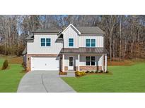 Charming two-story home featuring white siding, brick accents, covered porch, and an attached two-car garage at 205 Carrington Pt, Canton, GA 30115