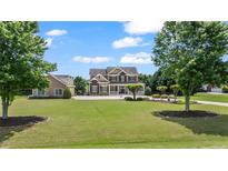 Inviting two-story home featuring a manicured lawn and a charming facade under a blue sky at 3920 Ineal Dr, Cumming, GA 30028