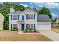 Charming two-story home featuring blue shutters, a manicured lawn, and an attached two-car garage at 512 Antler Ln, Suwanee, GA 30024