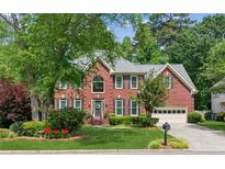 Charming two-story brick home featuring lush landscaping, a well-manicured lawn, and an attached two-car garage at 4140 Lansfaire Ter, Suwanee, GA 30024