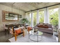 Bright living room features a neutral color palette, dining space, concrete ceilings and large windows overlooking the greenery at 480 John Wesley Dobbs Ne Ave # 418, Atlanta, GA 30312