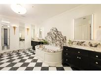Elegant bathroom features a marble-clad tub, dual vanities, and striking black-and-white checkered flooring at 3344 Peachtree Ne Rd # 3005, Atlanta, GA 30326