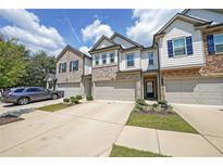 Townhouse exterior featuring brick and siding, two-car garage, driveway and small manicured landscaping at 1312 Cooper Springs Rd, Grayson, GA 30017